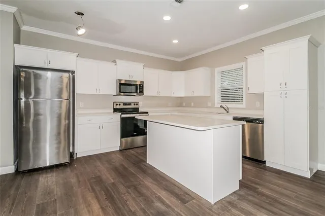 a kitchen with a refrigerator a stove top oven and white cabinets