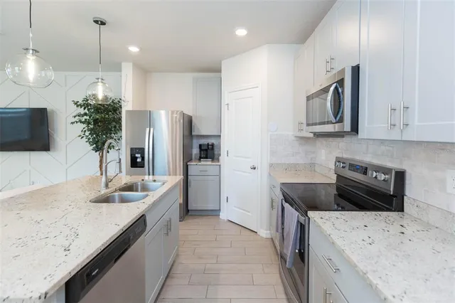 a kitchen with kitchen island a refrigerator a stove a microwave oven a sink with island and chairs