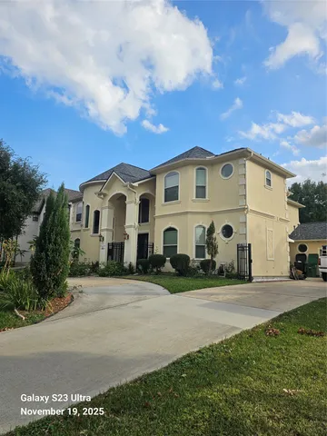 a view of a white house with a big yard and large trees