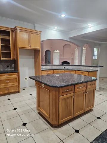 a view of an empty room with chandelier fan and wooden floor
