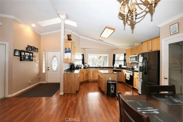 a living room with stainless steel appliances kitchen island granite countertop furniture and a wooden floor