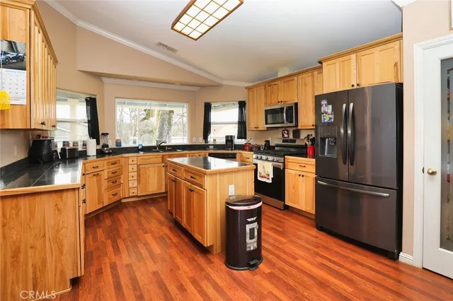 a kitchen with stainless steel appliances granite countertop a refrigerator a sink dishwasher a stove with wooden floors and cabinets