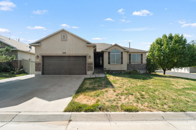 3396 Carmy Road Magna, UT 84044 - Photo 1 of 32 Exterior facade featuring a two-car garage, stone accents, and a prominent arched window