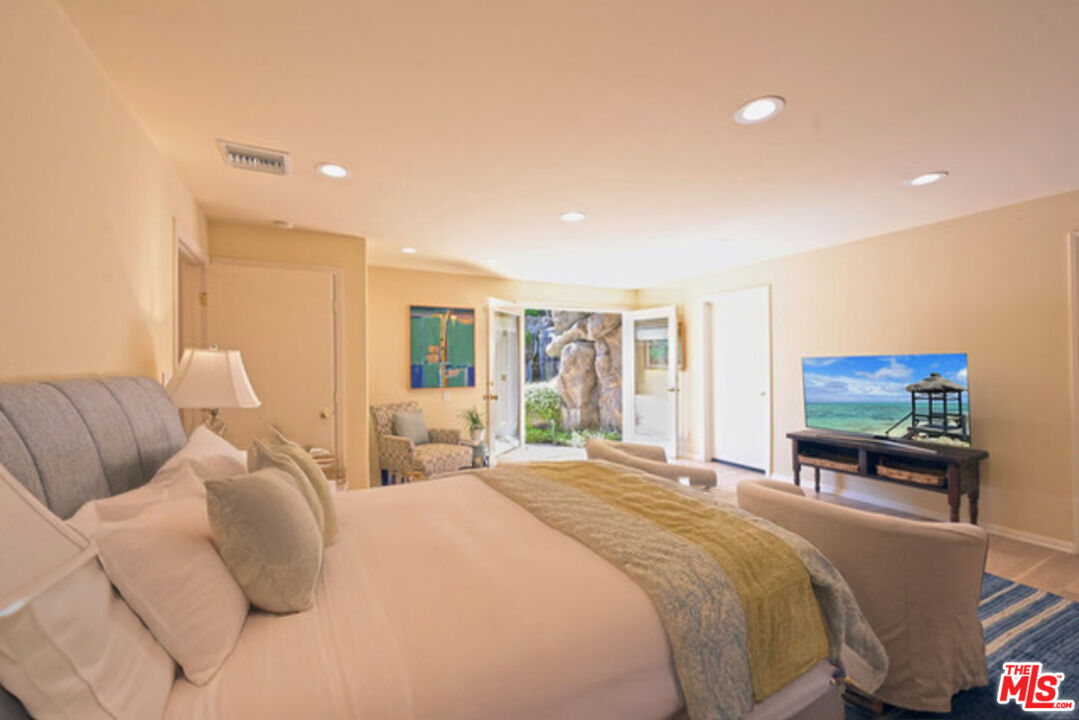 601 Tuallitan Road Los Angeles, CA 90049 - Photo 13 of 23 a large bedroom with a bed and a flat screen tv