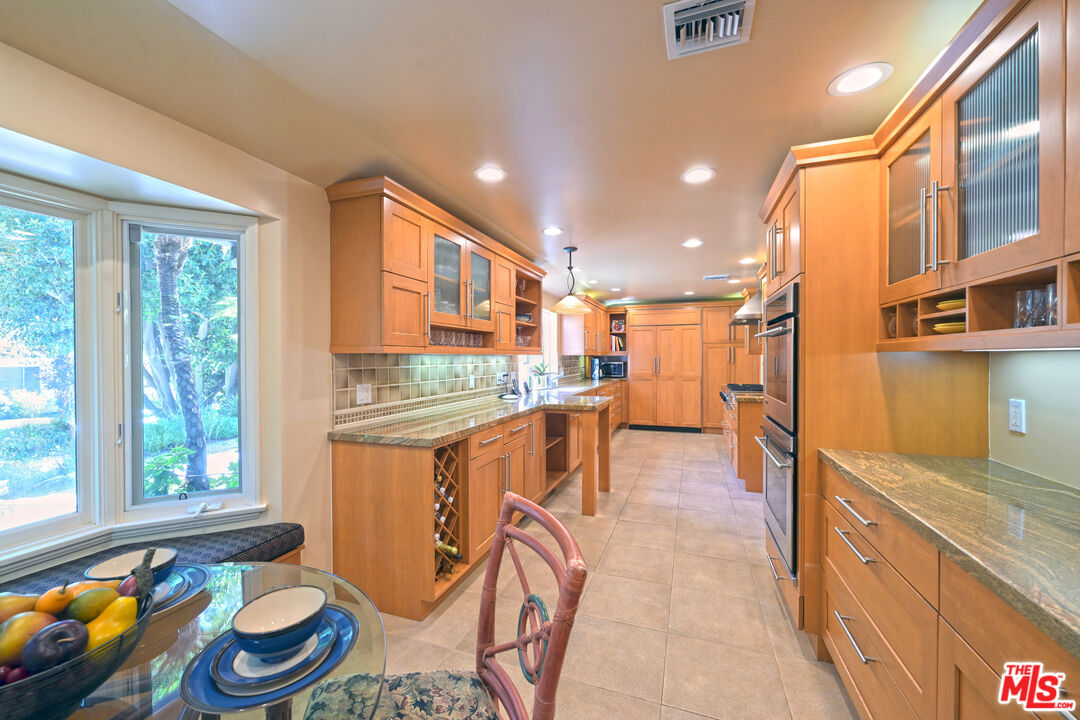 601 Tuallitan Road Los Angeles, CA 90049 - Photo 7 of 23 a kitchen view with granite countertop lots of clutter and stainless steel appliances