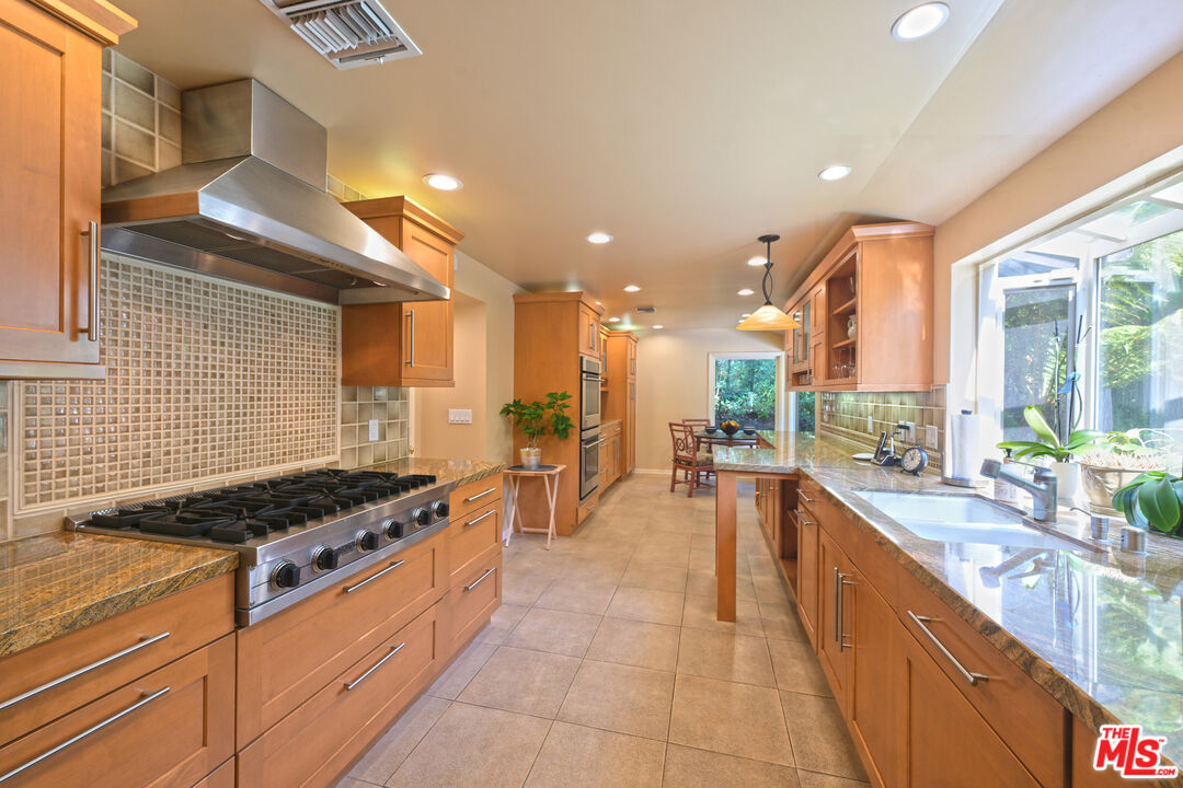 601 Tuallitan Road Los Angeles, CA 90049 - Photo 8 of 23 a kitchen with stainless steel appliances kitchen island granite countertop a stove and a sink