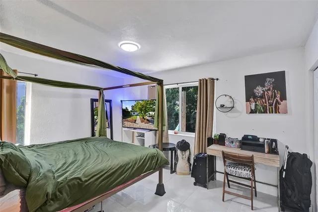 a bedroom with a bed a desk and chair with the wooden floor