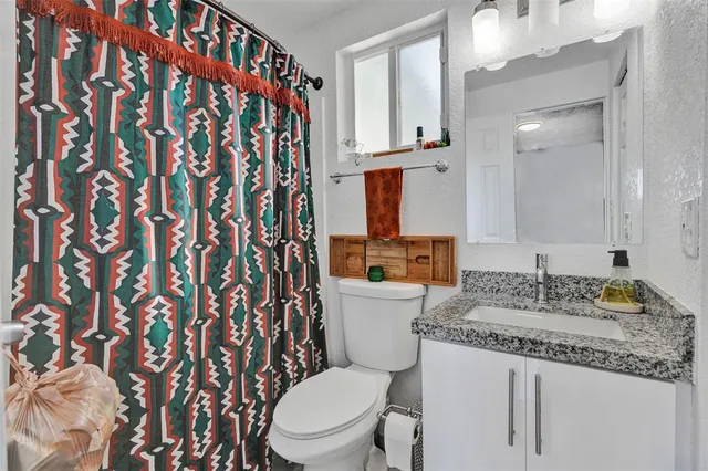 a bathroom with a granite countertop sink mirror vanity and toilet