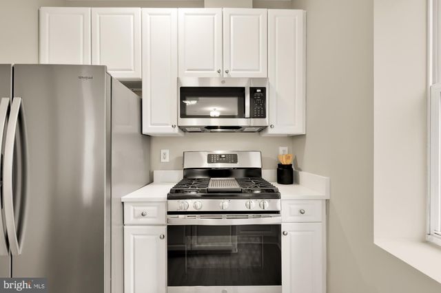 a kitchen with stainless steel appliances granite countertop white cabinets a refrigerator and a stove