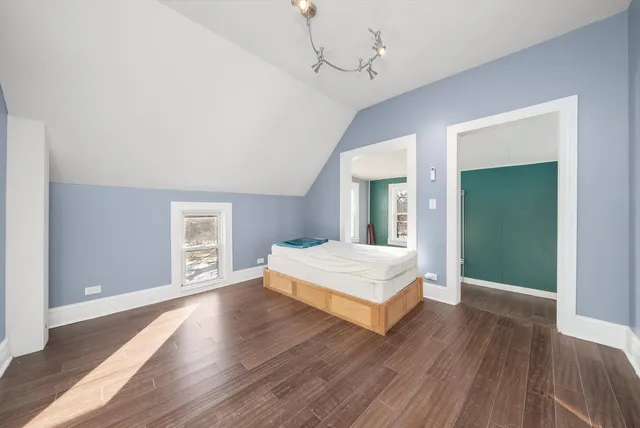 a spacious bedroom with a bed and wooden floor