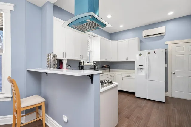 a kitchen with white cabinets and wooden floor