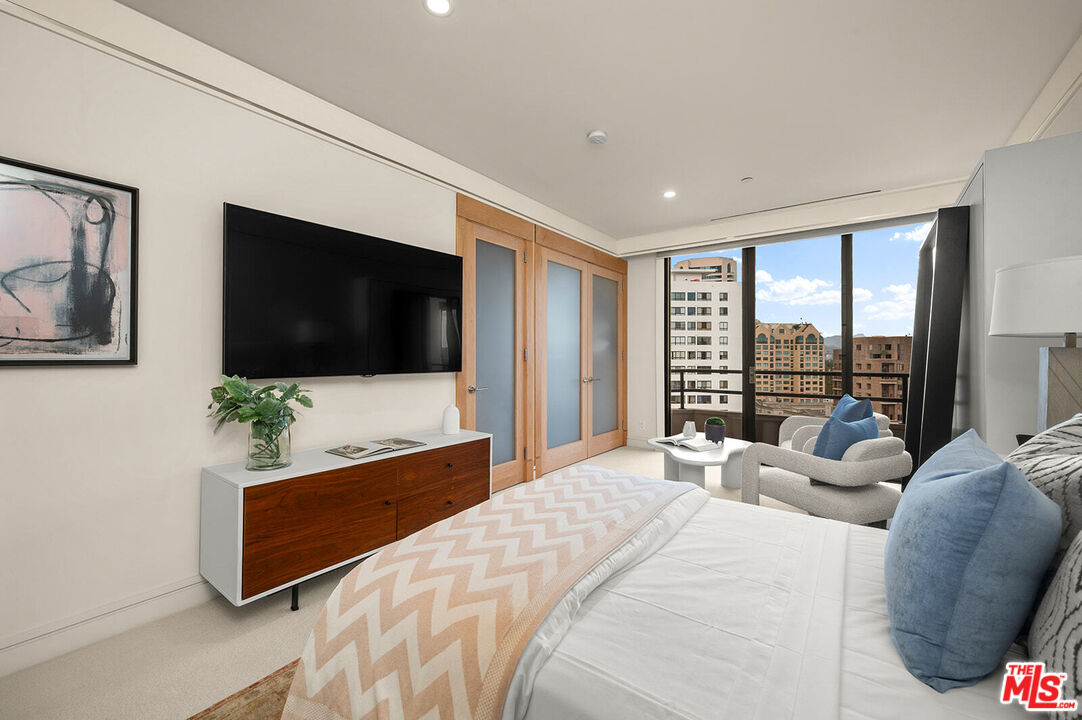 10601 Wilshire Boulevard, Unit 1201 Los Angeles, CA 90024 - Photo 26 of 48 a bedroom with a bed a flat screen tv and a couch
