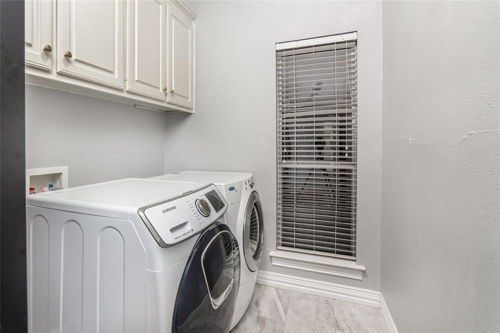 5801 Yeary Road Plano, TX 75093 - Photo 17 of 33 Dedicated utility space featuring overhead white cabinetry, a single window with blinds, and light-toned tile flooring
