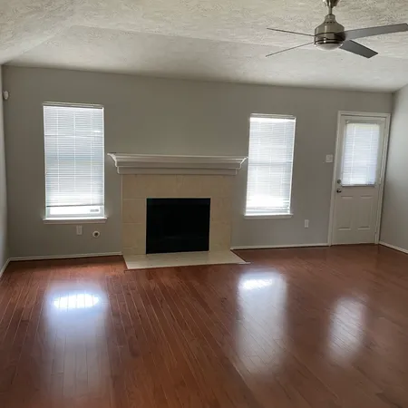 an empty room with wooden floor fireplace and windows