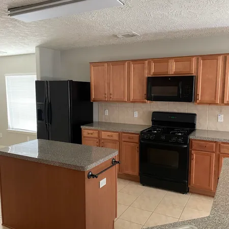 a kitchen with granite countertop a refrigerator and a stove top oven