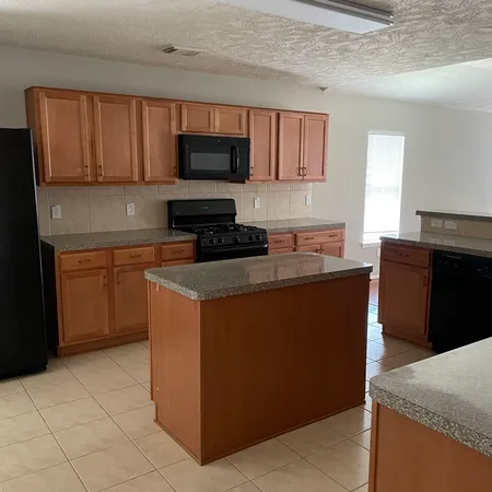 a kitchen with granite countertop a stove top oven microwave and cabinets