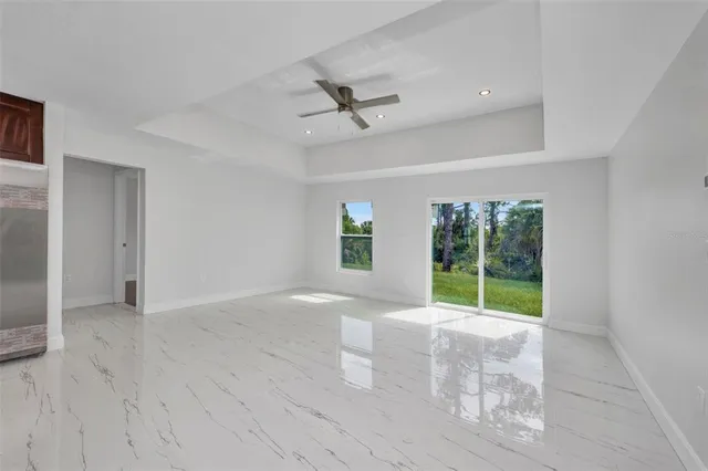a view of an empty room with a window and kitchen view