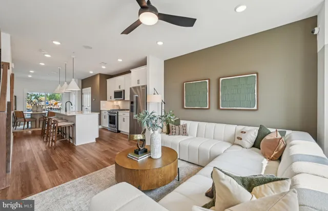 a living room with furniture kitchen view and a wooden floor