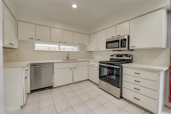 a kitchen with cabinets stainless steel appliances and a counter space
