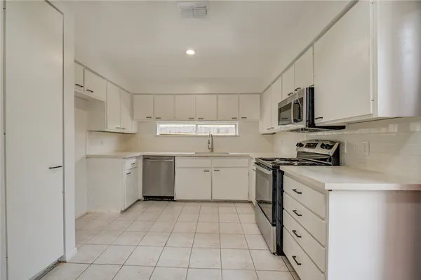 a kitchen with cabinets appliances a sink and a counter top space