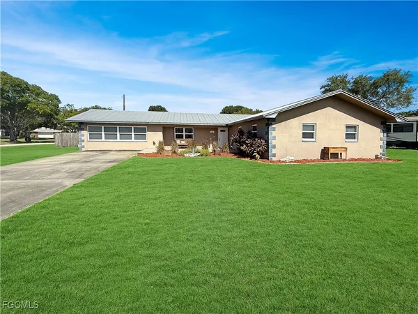 a view of a house with a big yard and large trees