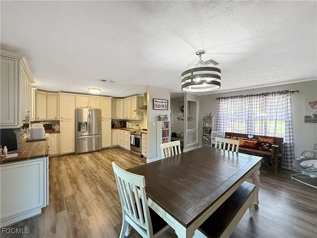 a living room with stainless steel appliances furniture a dining table and a chandelier