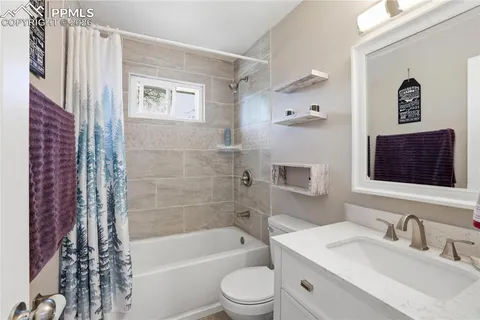 a bathroom with a bathtub shower sink vanity mirror and toilet