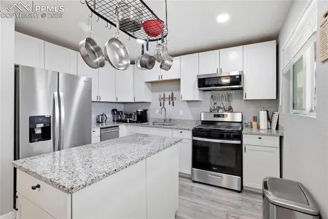 a kitchen with stainless steel appliances granite countertop a sink a stove and refrigerator