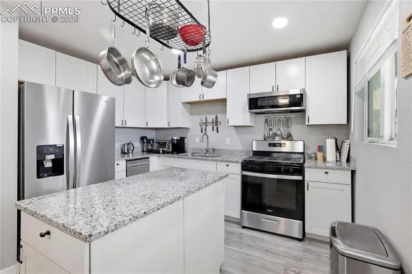a kitchen with stainless steel appliances granite countertop a sink a stove and refrigerator