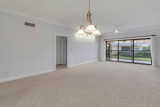 a view of a livingroom with a chandelier a ceiling fan and windows