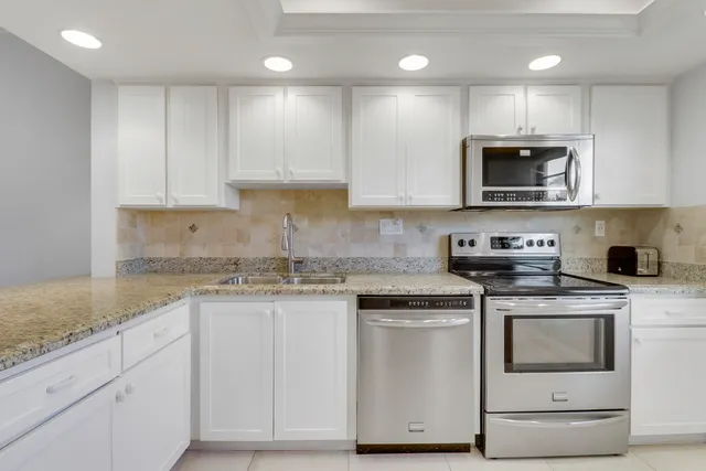 a kitchen with stainless steel appliances granite countertop a stove a sink and a microwave