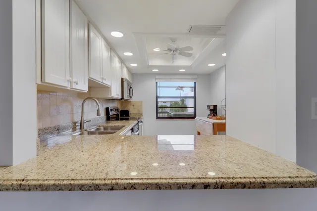 a kitchen with kitchen island granite countertop a sink window and refrigerator