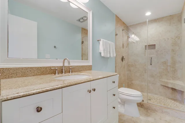 a bathroom with a granite countertop sink a toilet and a shower