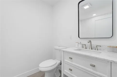 a bathroom with a granite countertop toilet sink mirror and vanity