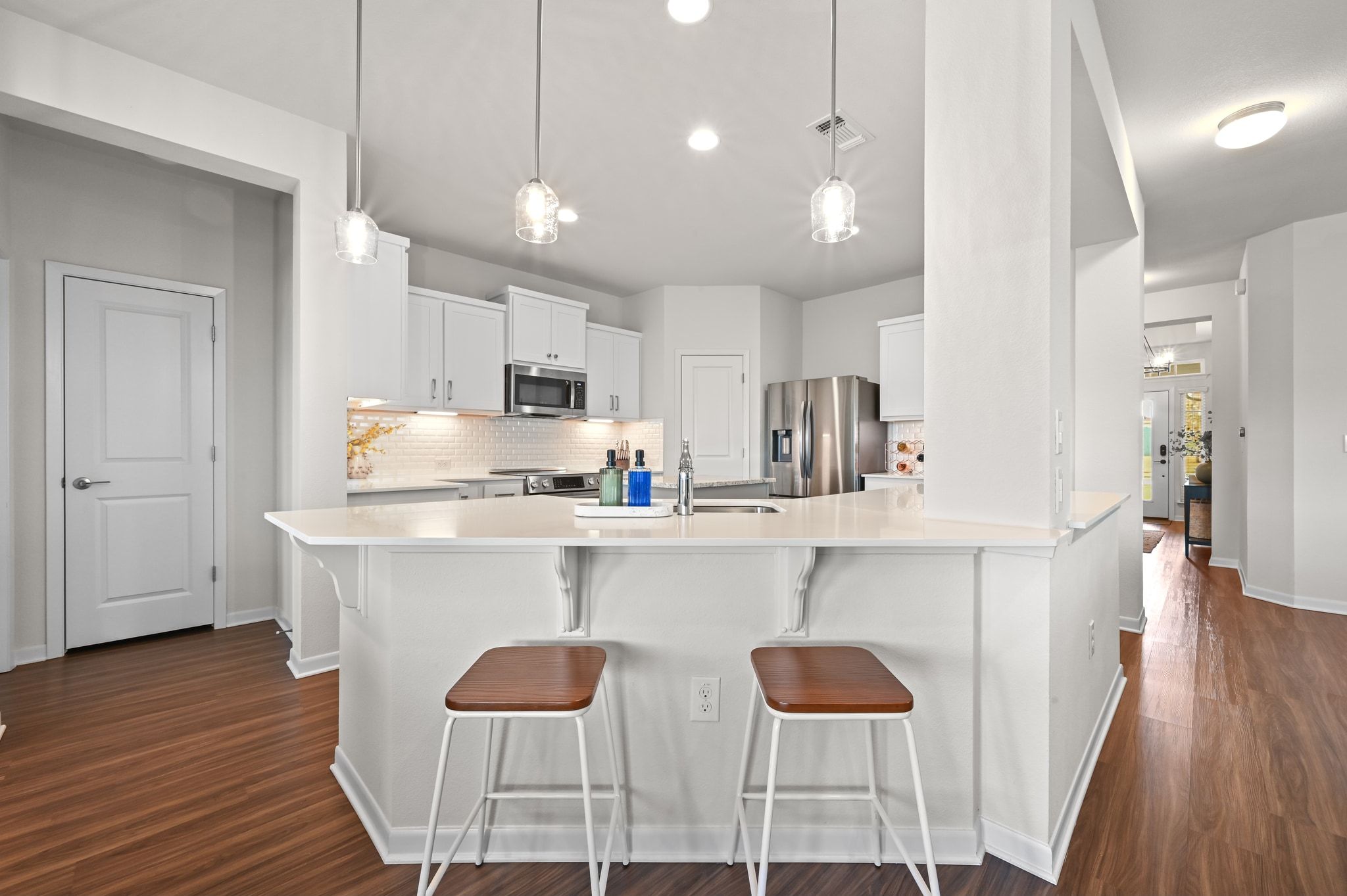 16620 Sumptuous Drive Manor, TX 78653 - Photo 14 of 40 Kitchen featuring white cabinetry, designer backsplash, designer light fixtures, stainless steel appliances, and light quartz counters
