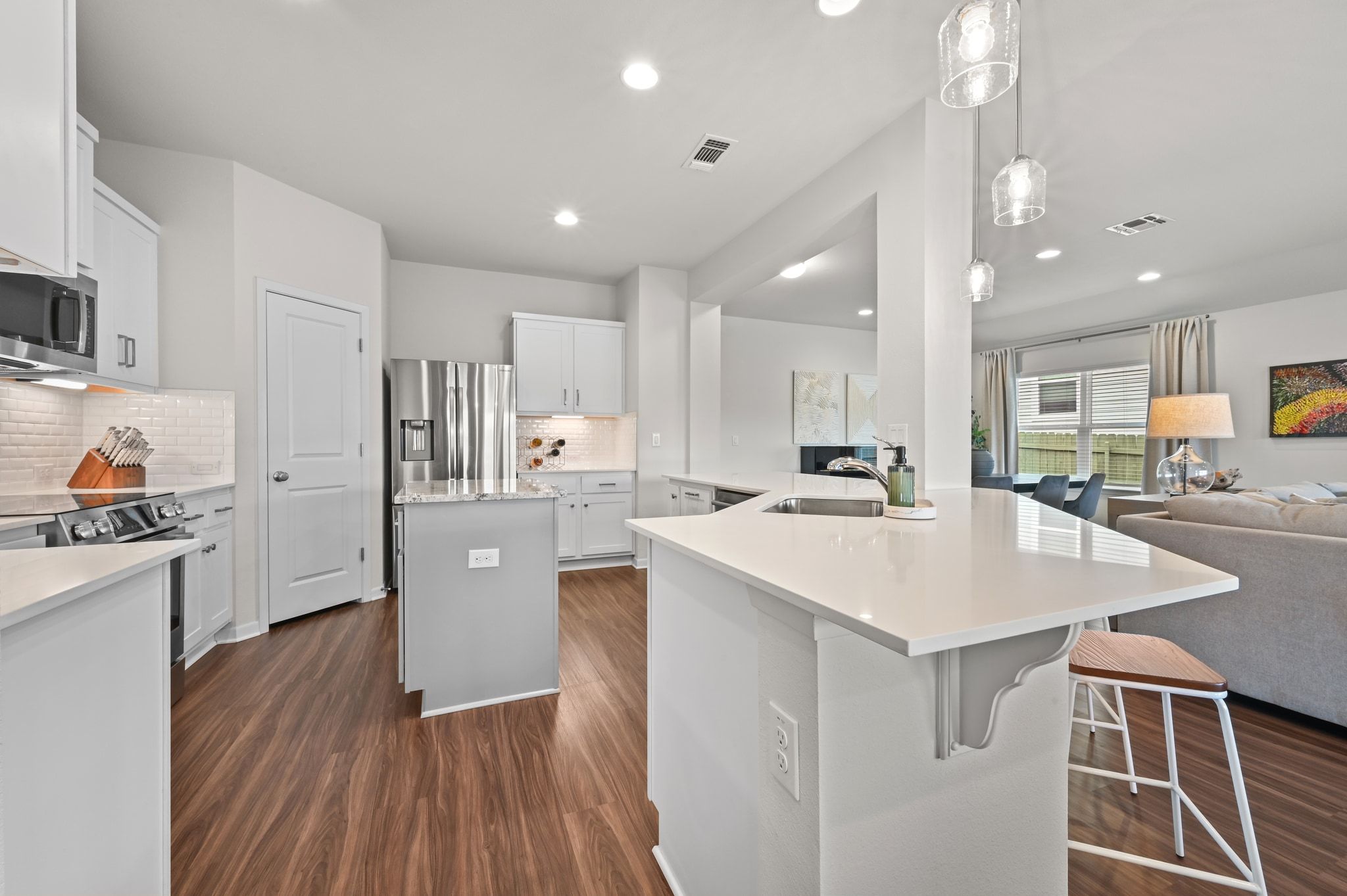 16620 Sumptuous Drive Manor, TX 78653 - Photo 39 of 40 Kitchen featuring open floor plan, a kitchen island, designer light fixtures, Bosch stainless steel appliances, white cabinetry, and quartz counters.