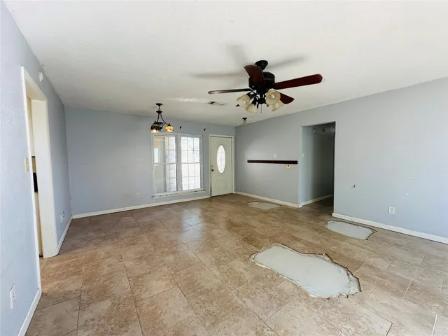 an empty room with chandelier fan and windows
