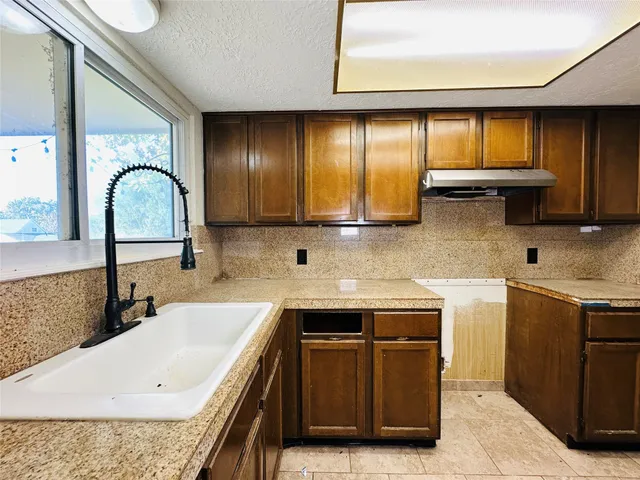 a kitchen with stainless steel appliances granite countertop a sink a stove and a wooden cabinets