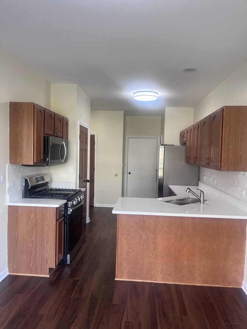 547 Goodwin Drive Bolingbrook, IL 60440 - Photo 5 of 36 a kitchen with stainless steel appliances granite countertop a sink a stove a refrigerator cabinets and wooden floor