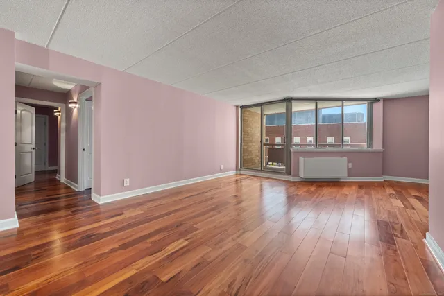 a view of an empty room with wooden floor and a window