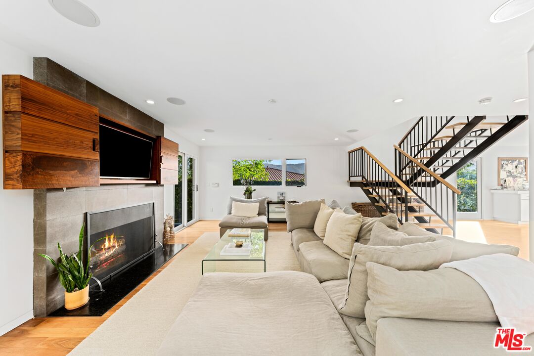 13501 Bayliss Road Los Angeles, CA 90049 - Photo 4 of 33 a living room with furniture a fireplace and a flat screen tv