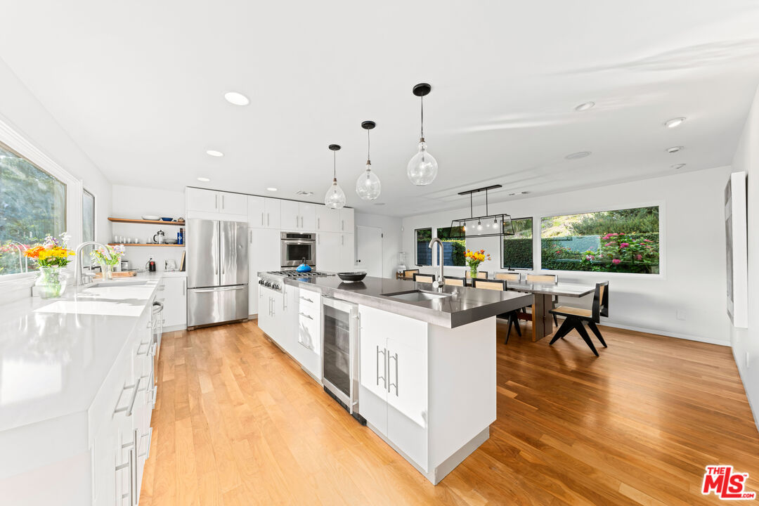 13501 Bayliss Road Los Angeles, CA 90049 - Photo 6 of 33 a kitchen with stainless steel appliances kitchen island a large counter space and wooden floors
