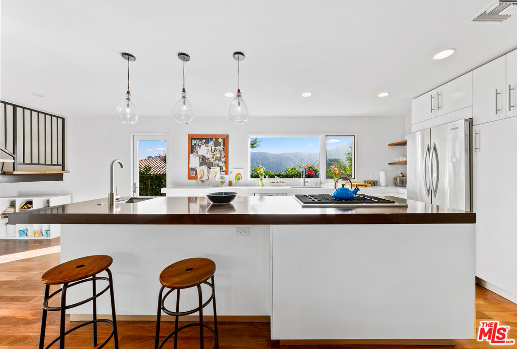 13501 Bayliss Road Los Angeles, CA 90049 - Photo 10 of 33 a kitchen with stainless steel appliances granite countertop a table chairs sink and cabinets