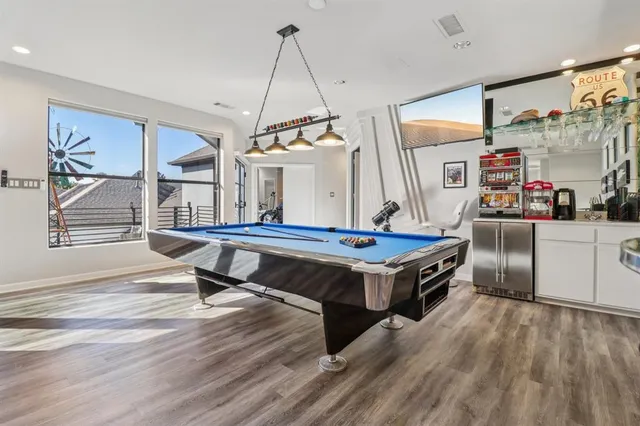 a room with wooden floors pool table and windows