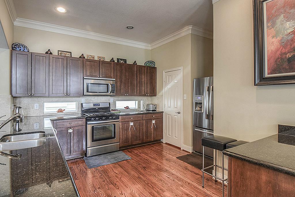 1137 West 24th Street, Unit A Houston, TX 77008 - Photo 9 of 40 a kitchen with stainless steel appliances granite countertop a stove top oven a sink dishwasher a refrigerator and cabinets with wooden floor