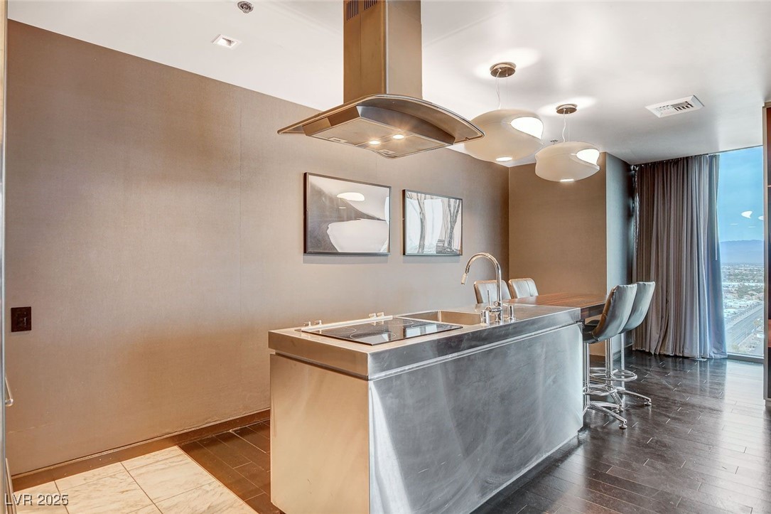4381 West Flamingo Road, Unit 2202 Las Vegas, NV 89103 - Photo 16 of 40 Kitchen featuring island range hood, black electric stovetop, an island with sink, dark wood-type flooring, and pendant lighting