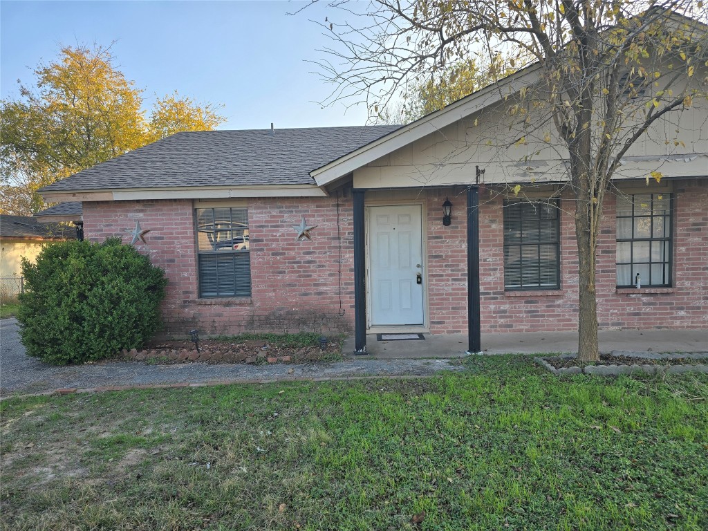 a view of a brick house with a yard and large tree