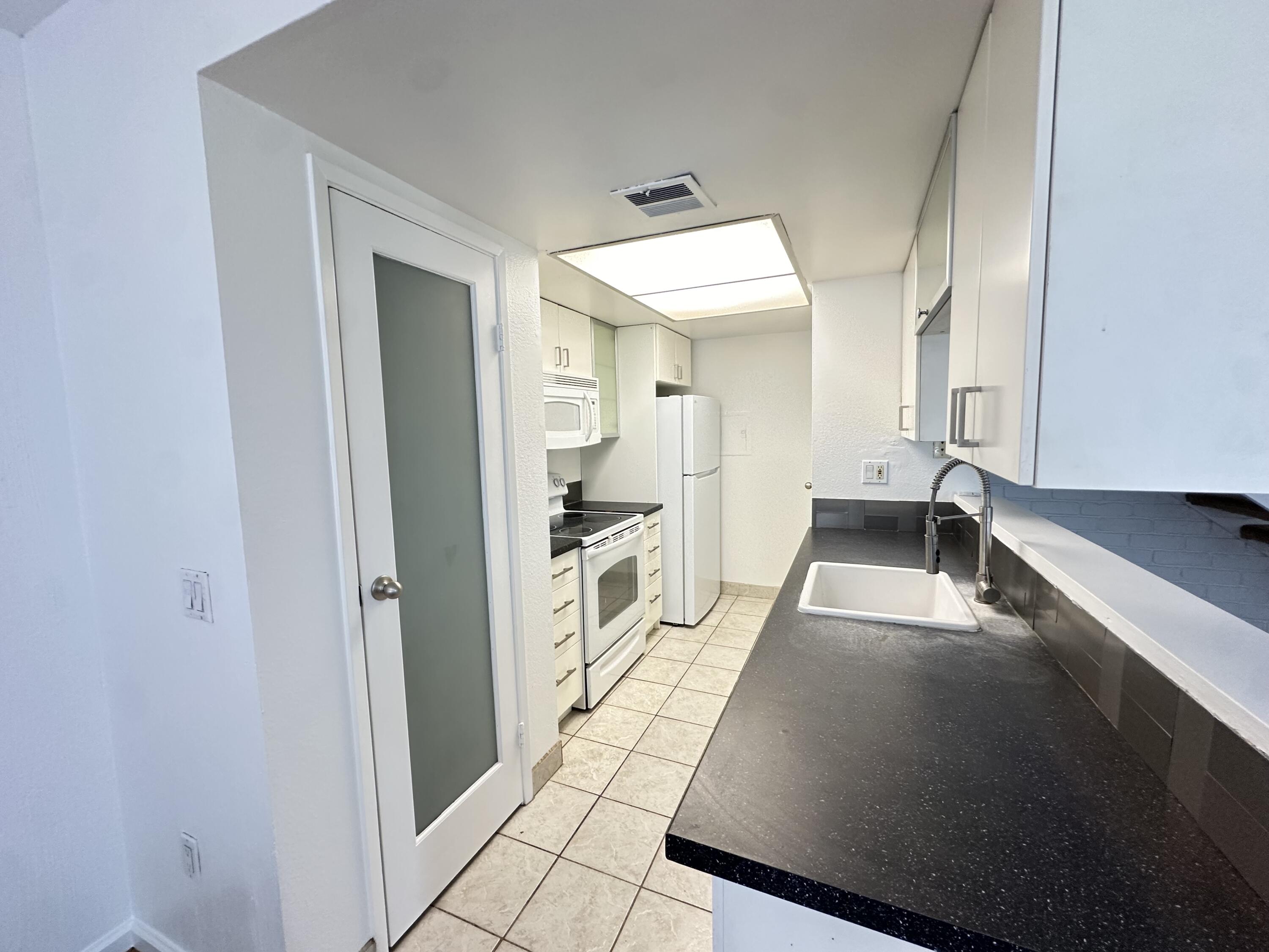 72631 Thrush Road, Unit 2 Palm Desert, CA 92260 - Photo 5 of 20 a kitchen with granite countertop white cabinets and stainless steel appliances