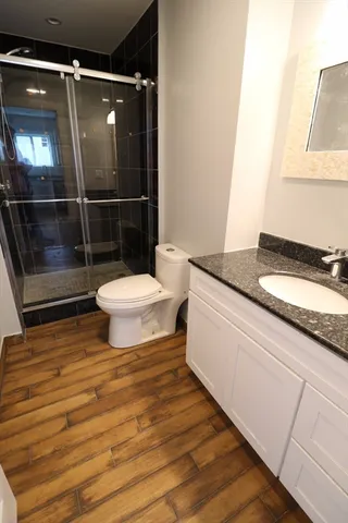 a bathroom with a granite countertop toilet sink and mirror