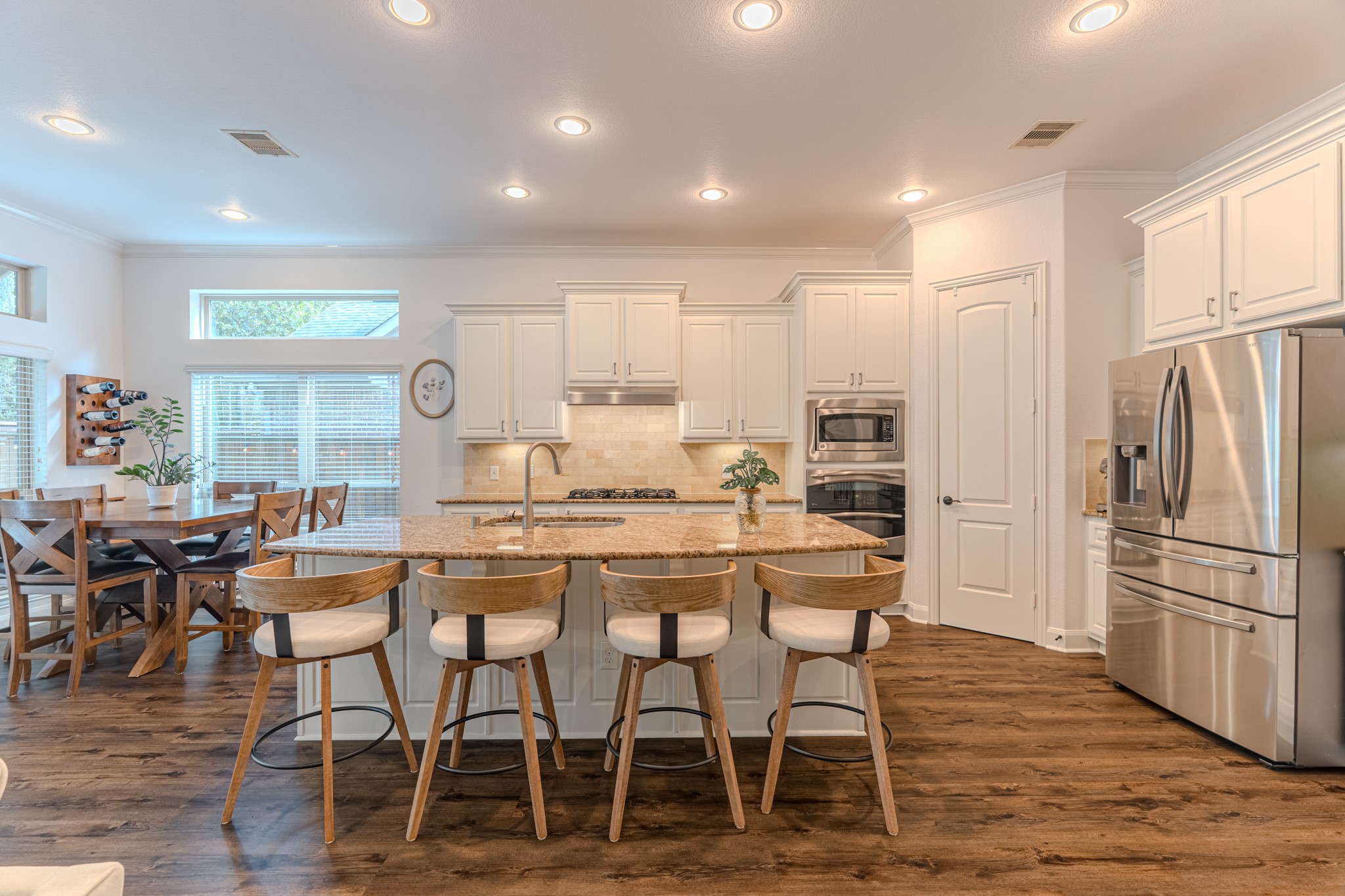 30 Fury Ranch Place The Woodlands, TX 77375 - Photo 15 of 47 This kitchen features a spacious, open layout with modern appliances, a central island with bar seating, and ample natural light from large windows. The dining area is cozy and integrates seamlessly with the kitchen, while the elegant cabinetry and wood flooring add warmth and style.